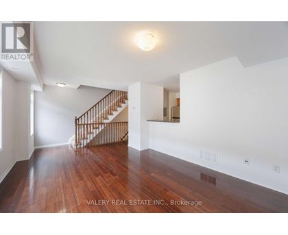 A spacious room with wooden floors and a staircase.