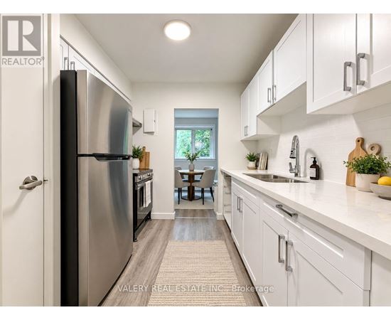 A modern kitchen with white cabinets and a stainless steel refrigerator.