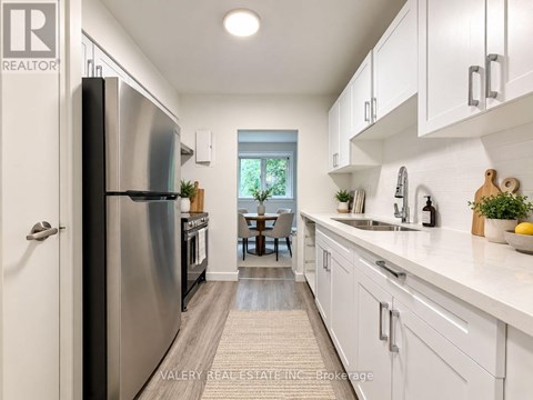 A modern kitchen with white cabinets and a stainless steel refrigerator.