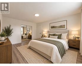 A bedroom with a large bed, a nightstand with a lamp, and a framed picture on the wall.