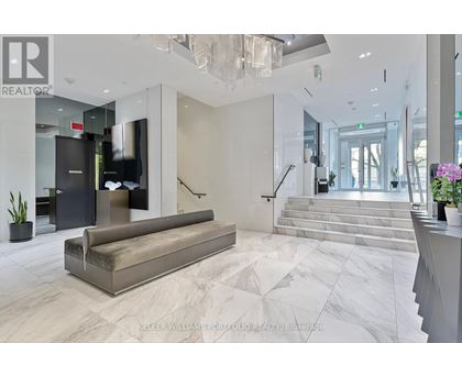 A spacious lobby with a marble floor and a staircase leading to the second floor.