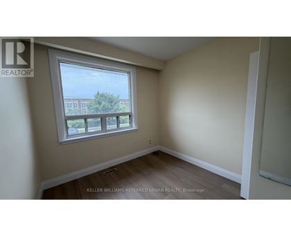 A room with a window showing a view of a building and trees outside.