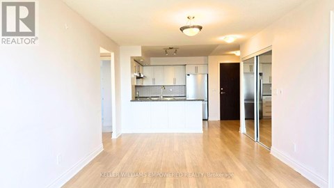 A spacious kitchen with white cabinets and a wooden floor.