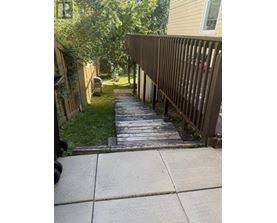 A wooden fence runs along the side of a concrete walkway.