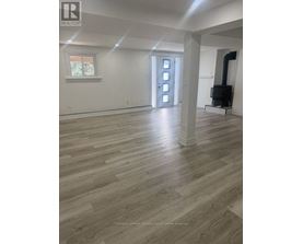 A large empty room with wood flooring and white walls.