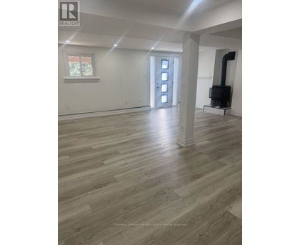 A large empty room with wood flooring and white walls.