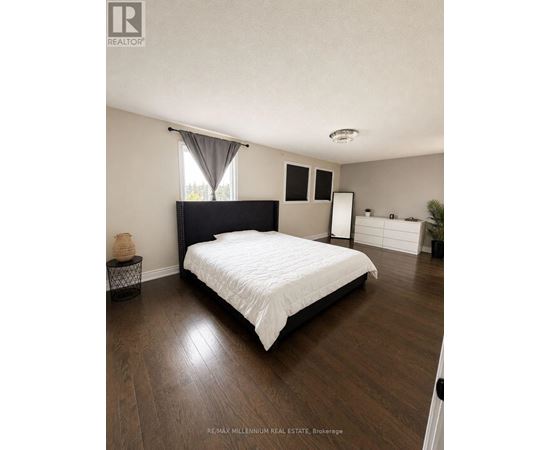 A bedroom with a large bed and a small table with a vase on it.