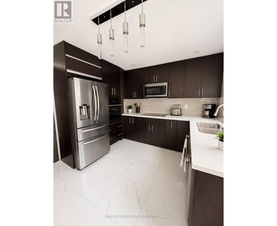 A modern kitchen with a stainless steel refrigerator and dark brown cabinets.