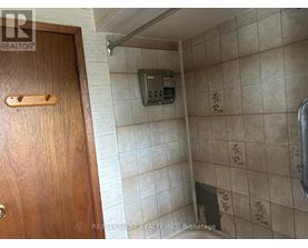 A bathroom with a wooden door and a tiled wall.