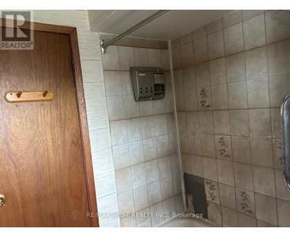 A bathroom with a wooden door and a tiled wall.