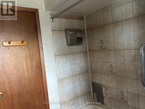 A bathroom with a wooden door and a tiled wall.