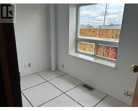 A room with a window showing a view of a parking lot.