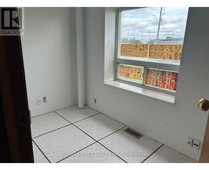 A room with a window showing a view of a parking lot.