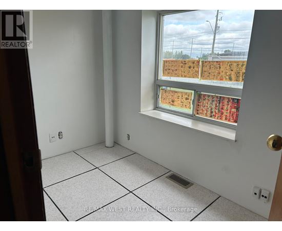 A room with a window showing a view of a parking lot.