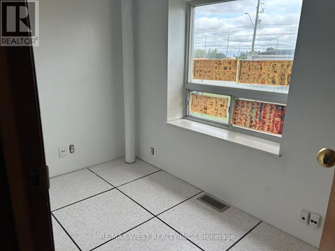 A room with a window showing a view of a parking lot.