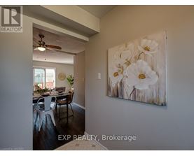 A dining room with a table set for four and a painting of white flowers on the wall.