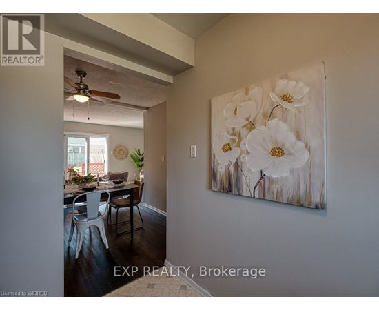 A dining room with a table set for four and a painting of white flowers on the wall.