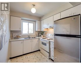 A kitchen with white cabinets and a black refrigerator.