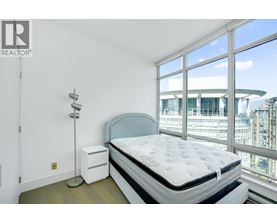 A bedroom with a large bed and a window overlooking a cityscape.
