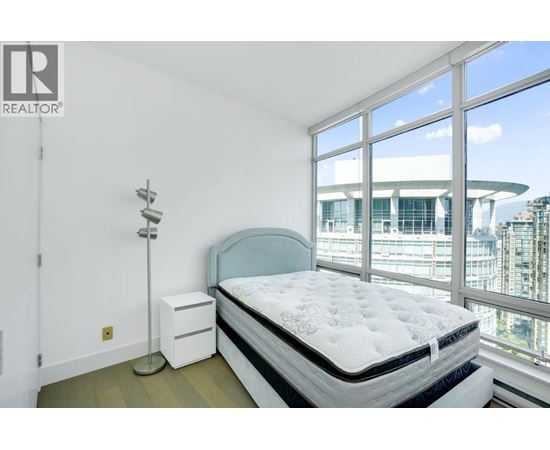 A bedroom with a large bed and a window overlooking a cityscape.