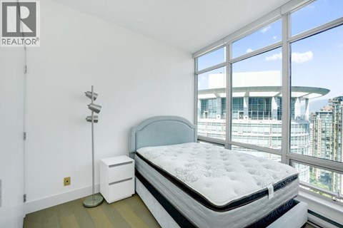 A bedroom with a large bed and a window overlooking a cityscape.