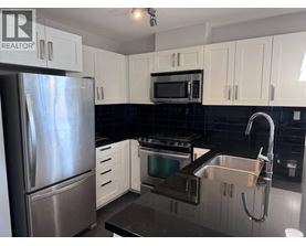 A kitchen with a stainless steel refrigerator, microwave, oven, and sink.