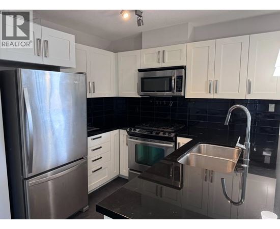 A kitchen with a stainless steel refrigerator, microwave, oven, and sink.