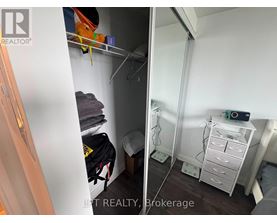 A small bedroom with a white wardrobe and a white bedside table.