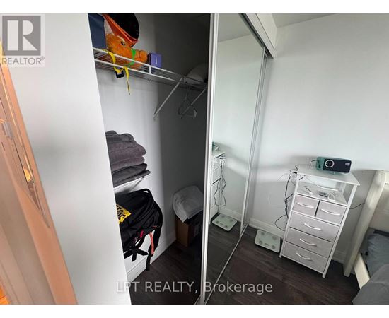 A small bedroom with a white wardrobe and a white bedside table.