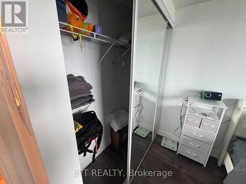 A small bedroom with a white wardrobe and a white bedside table.