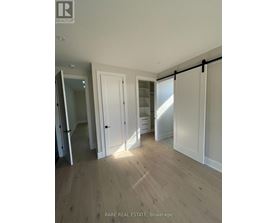 A room with wooden flooring and white walls, with a sliding door and a mirror.
