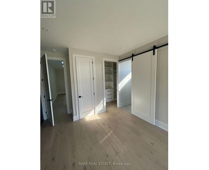 A room with wooden flooring and white walls, with a sliding door and a mirror.