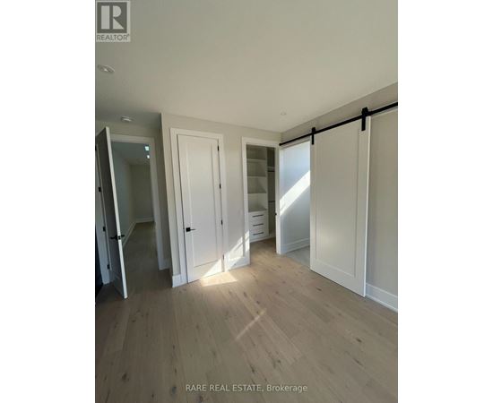 A room with wooden flooring and white walls, with a sliding door and a mirror.