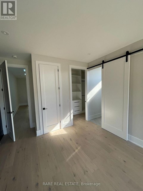 A room with wooden flooring and white walls, with a sliding door and a mirror.