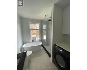 A modern bathroom with a large tub and a washer and dryer built into the cabinetry.