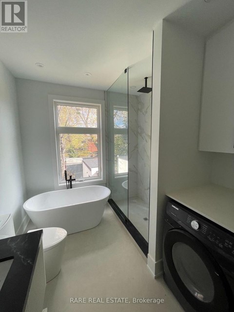 A modern bathroom with a large tub and a washer and dryer built into the cabinetry.
