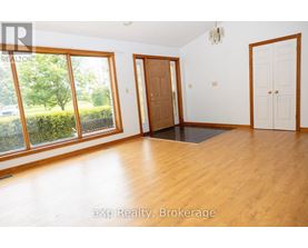 A room with wooden floors and white walls, with a door and a window.