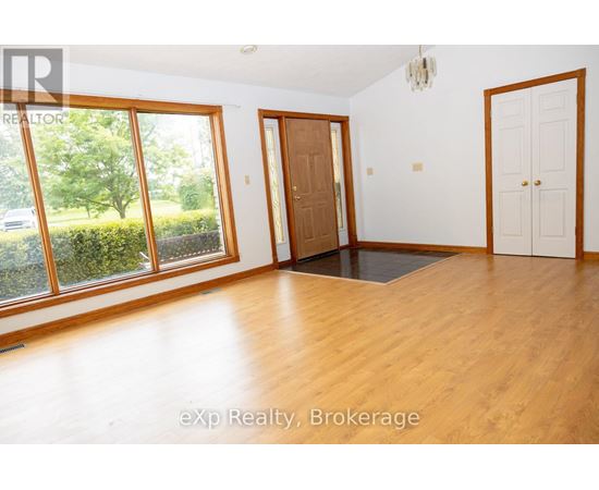 A room with wooden floors and white walls, with a door and a window.