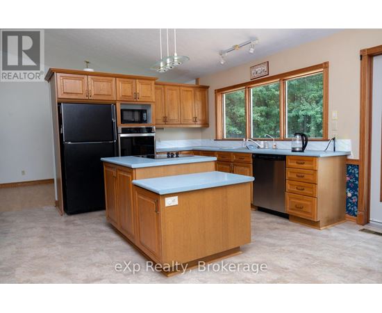 A kitchen with wooden cabinets and a black refrigerator.