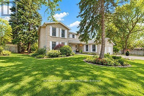 A large house with a well-manicured lawn and trees in the background.