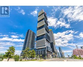 A tall, modern building with a glass facade stands under a blue sky with scattered clouds.