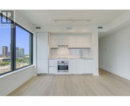 A spacious kitchen with white cabinets and a large window overlooking the city.