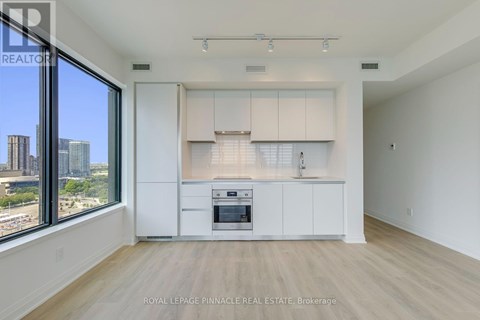 A spacious kitchen with white cabinets and a large window overlooking the city.