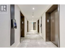 A hallway with elevator doors on the right and a realtor sign on the left.