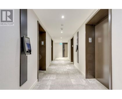 A hallway with elevator doors on the right and a realtor sign on the left.