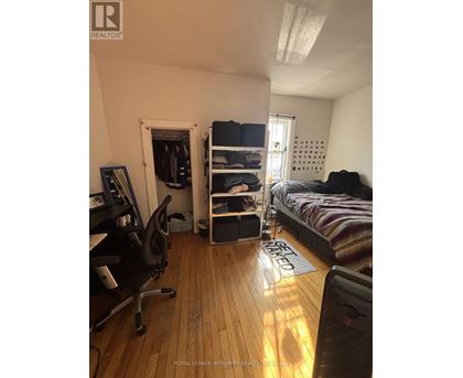 A bedroom with a bed, chair, and a window.