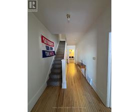 A long hallway with a staircase and a sign on the wall.
