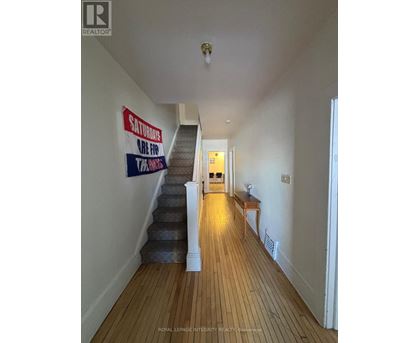 A long hallway with a staircase and a sign on the wall.