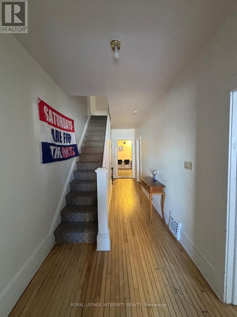 A long hallway with a staircase and a sign on the wall.