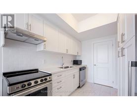 A white kitchen with a stove top oven and microwave.